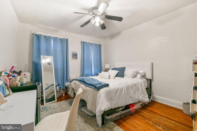 bedroom featuring a ceiling fan, baseboards, and wood finished floors