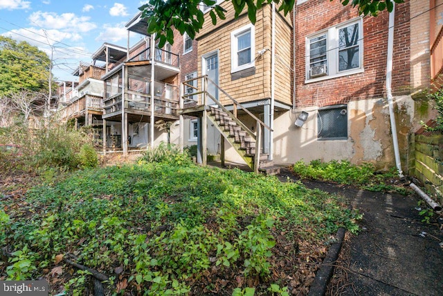 rear view of house featuring stairs and brick siding