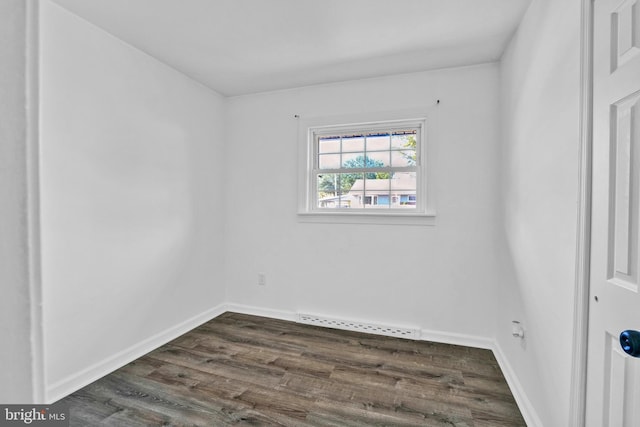 unfurnished room with dark wood-style flooring and baseboards