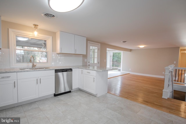 kitchen featuring dishwasher, open floor plan, a peninsula, white cabinetry, and a sink