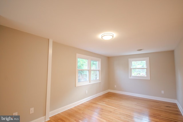 unfurnished room featuring light wood-style floors, a healthy amount of sunlight, and baseboards