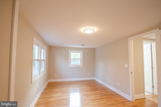 spare room featuring baseboards and light wood-style floors