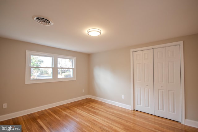 unfurnished bedroom featuring light wood finished floors, a closet, visible vents, and baseboards