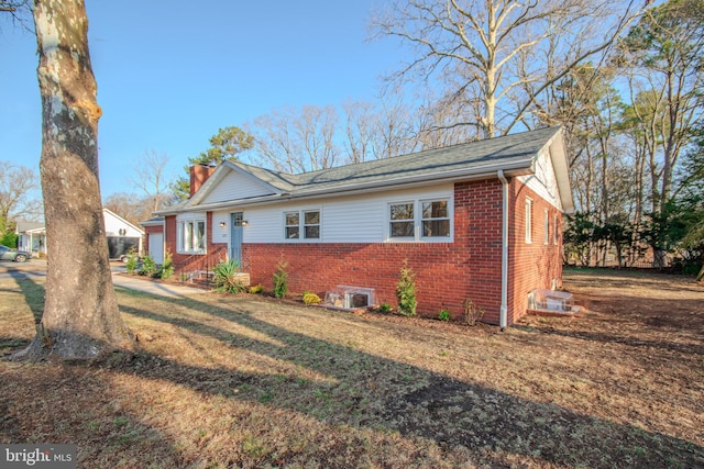 view of front of property with brick siding, a chimney, and a front yard