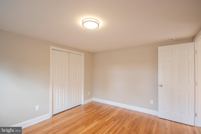 unfurnished bedroom with light wood-type flooring, a closet, and baseboards