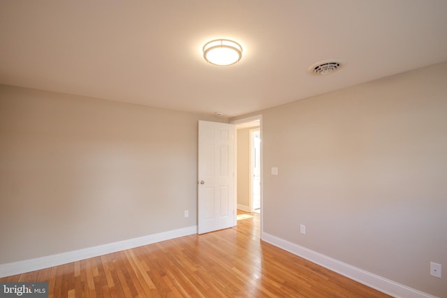 empty room featuring light wood finished floors, visible vents, and baseboards