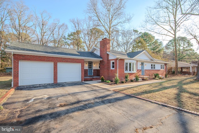 ranch-style home with an attached garage, brick siding, driveway, a front lawn, and a chimney