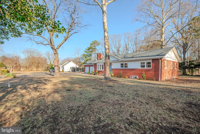 single story home with a garage, brick siding, and a chimney