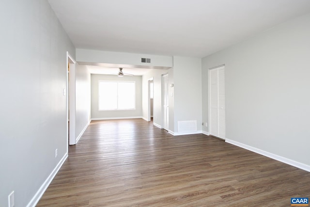 empty room with a ceiling fan, visible vents, baseboards, and wood finished floors