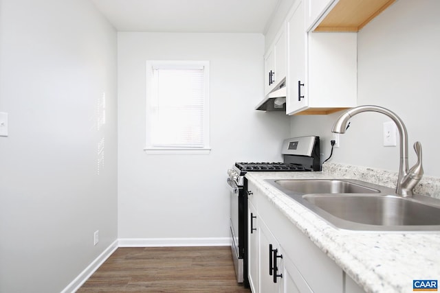 kitchen with baseboards, white cabinetry, a sink, under cabinet range hood, and stainless steel gas range oven