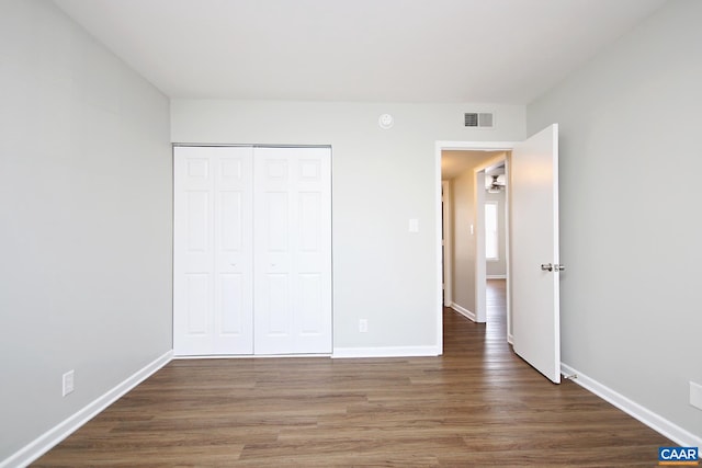 unfurnished bedroom with baseboards, a closet, visible vents, and wood finished floors