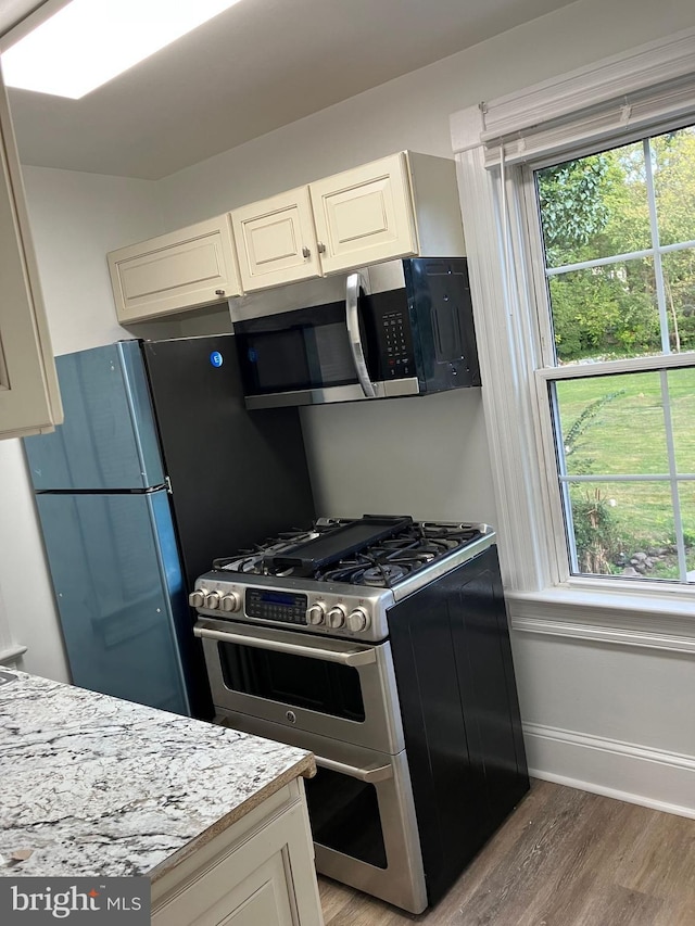 kitchen featuring appliances with stainless steel finishes, white cabinets, baseboards, and light wood finished floors