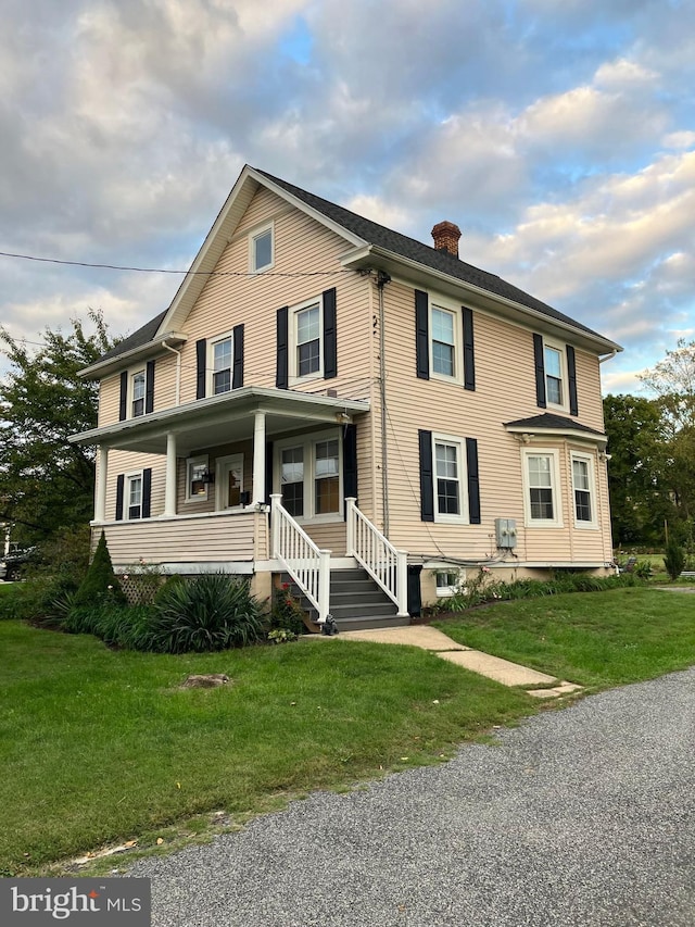 view of front of home featuring a porch, a front yard, and a chimney