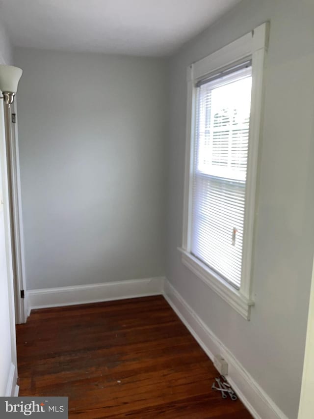 empty room featuring baseboards and dark wood-style flooring