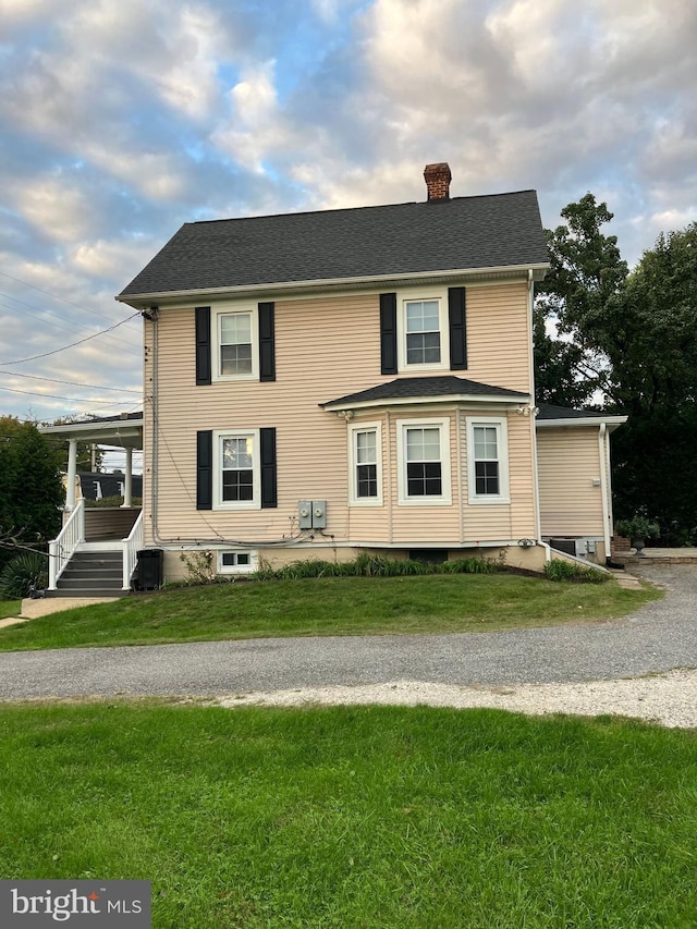 view of front of property featuring a chimney, a front lawn, and roof with shingles