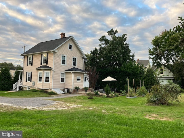 view of front of house featuring entry steps, central air condition unit, a chimney, and a front yard