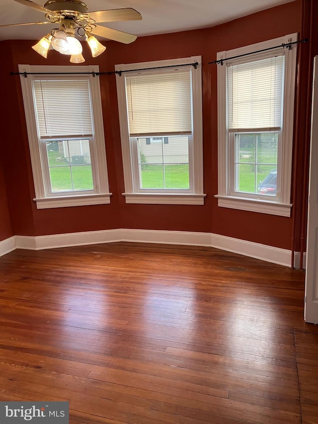 unfurnished room with baseboards, wood finished floors, and a healthy amount of sunlight