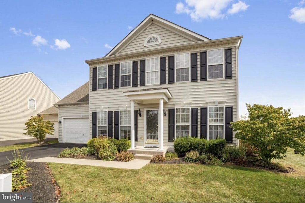 view of front of property featuring a garage, driveway, and a front yard