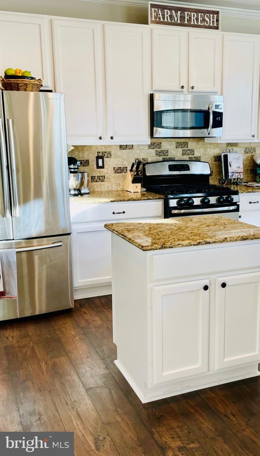 kitchen with backsplash, appliances with stainless steel finishes, dark wood-type flooring, white cabinets, and light stone countertops