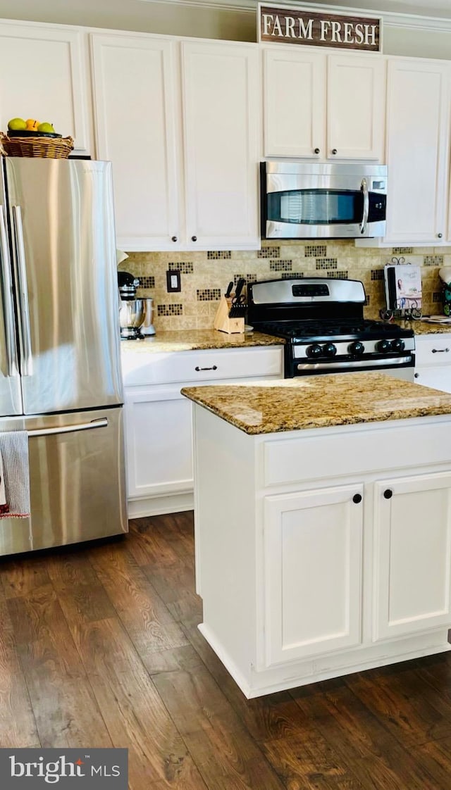 kitchen with backsplash, appliances with stainless steel finishes, dark wood-type flooring, white cabinets, and light stone countertops