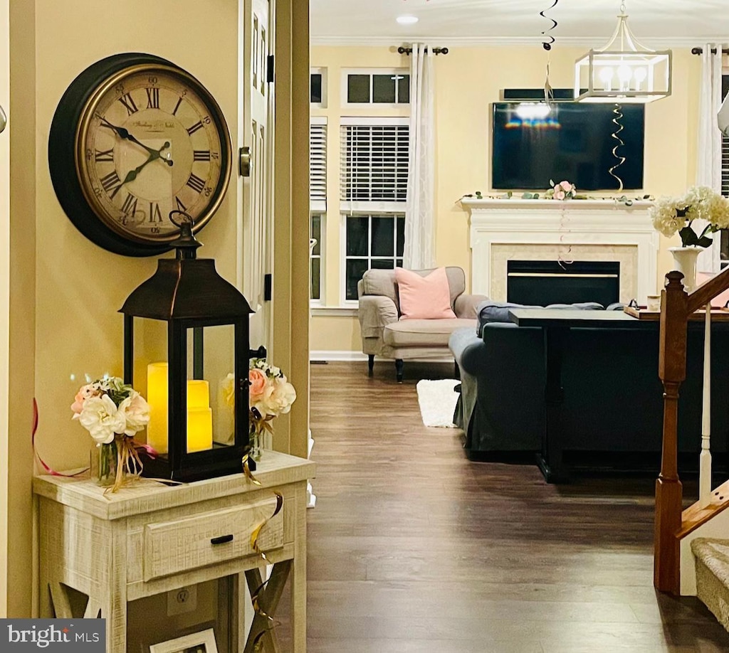 living area with a chandelier, a fireplace, wood finished floors, stairway, and crown molding