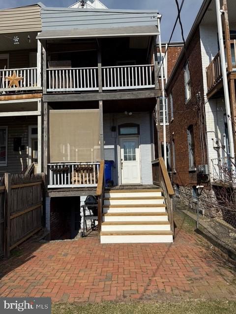 view of front of house featuring a balcony, fence, and brick siding