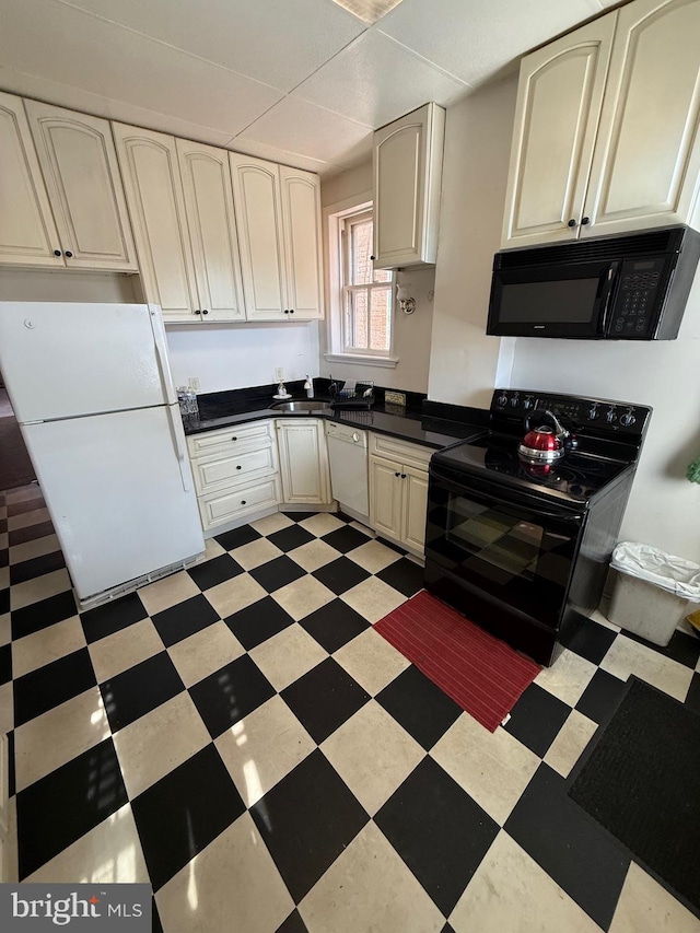 kitchen with black appliances, light floors, dark countertops, and a sink