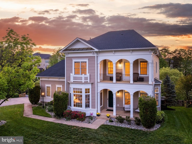view of front facade with a porch, a standing seam roof, roof with shingles, a balcony, and a yard