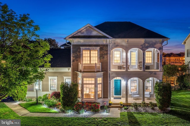 view of front of property featuring a porch, a lawn, a shingled roof, and a balcony