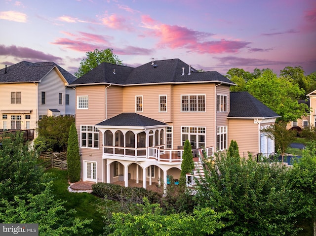 back of property with a shingled roof, a sunroom, stairway, french doors, and a patio
