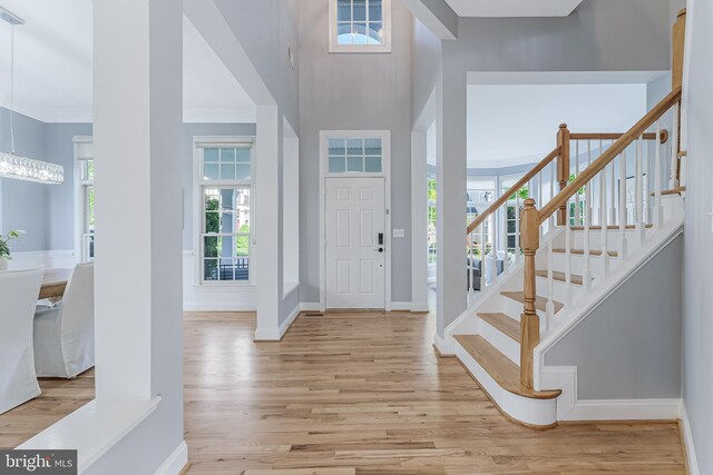 foyer entrance with crown molding, baseboards, stairs, and wood finished floors