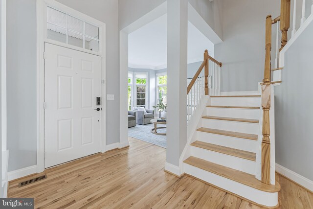 foyer with visible vents, baseboards, wood finished floors, and stairway