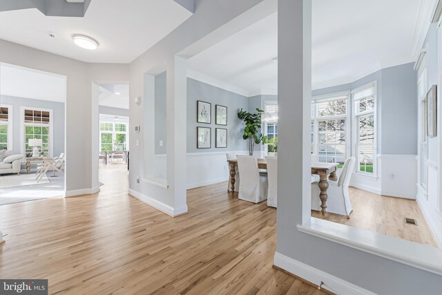 entryway with crown molding, baseboards, light wood finished floors, and visible vents