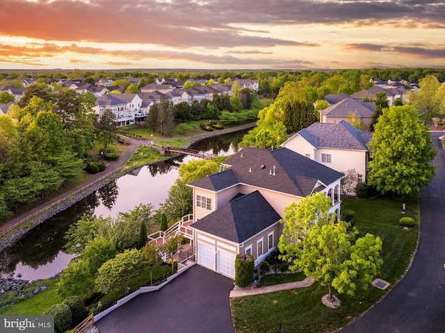aerial view at dusk featuring a water view and a residential view