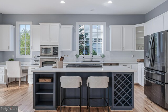 kitchen with a sink, appliances with stainless steel finishes, white cabinets, and open shelves
