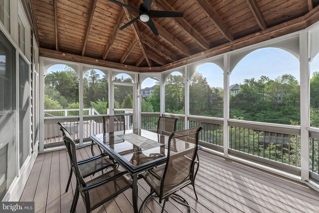 sunroom with outdoor dining area, ceiling fan, and beam ceiling