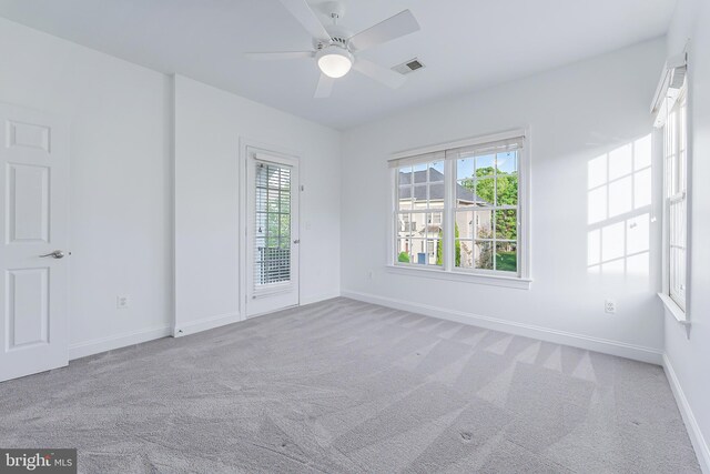 carpeted spare room with visible vents, baseboards, and ceiling fan