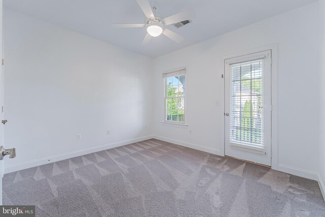 carpeted spare room with a ceiling fan, baseboards, visible vents, and a healthy amount of sunlight