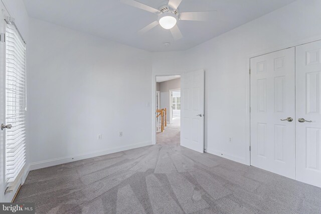 unfurnished bedroom featuring baseboards, a ceiling fan, carpet, and a closet