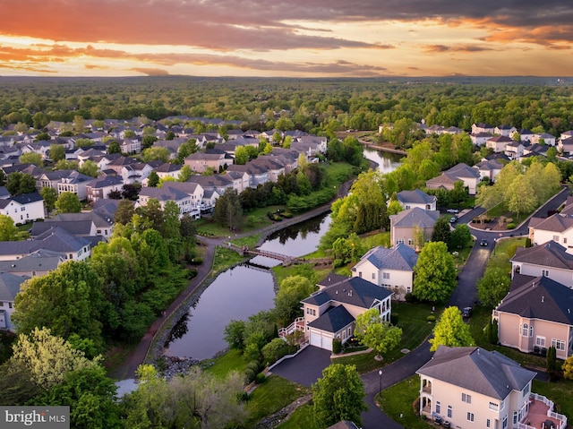aerial view at dusk with a water view and a residential view