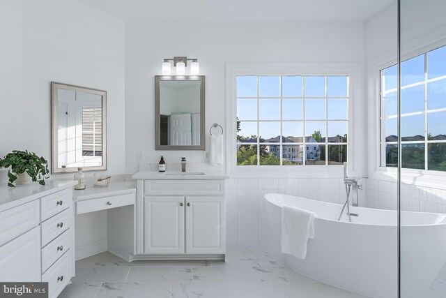 bathroom with a freestanding bath, vanity, plenty of natural light, and marble finish floor