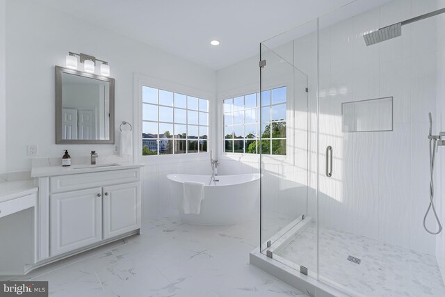 full bath featuring vanity, a freestanding tub, a stall shower, and marble finish floor