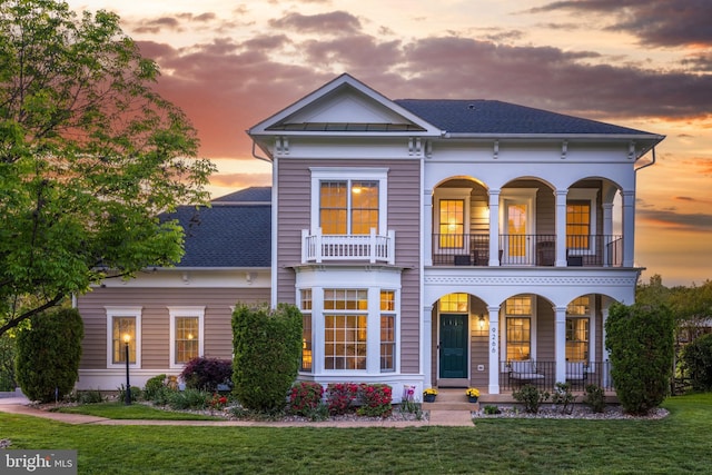 view of front of house with a porch, a shingled roof, a yard, and a balcony