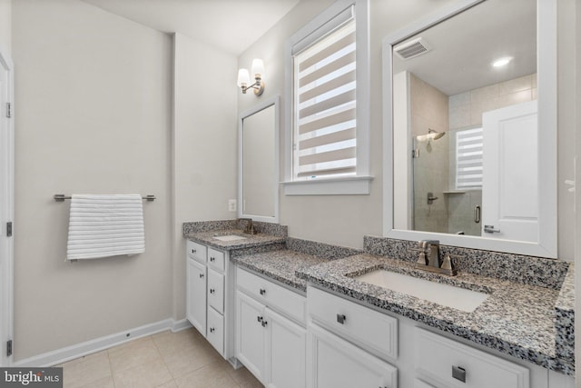 full bathroom featuring double vanity, tile patterned floors, a stall shower, and a sink