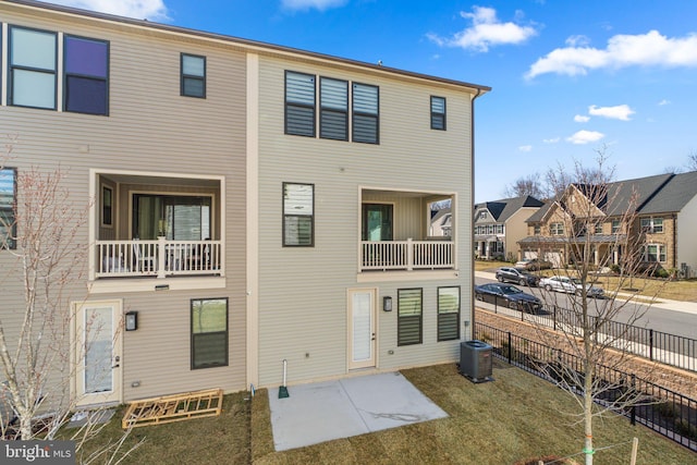 rear view of property with a patio, central AC unit, fence, and a residential view