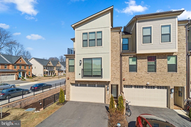 view of property with aphalt driveway, fence, a residential view, a garage, and brick siding