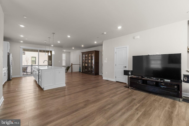 kitchen featuring white cabinetry, wood finished floors, open floor plan, and a sink