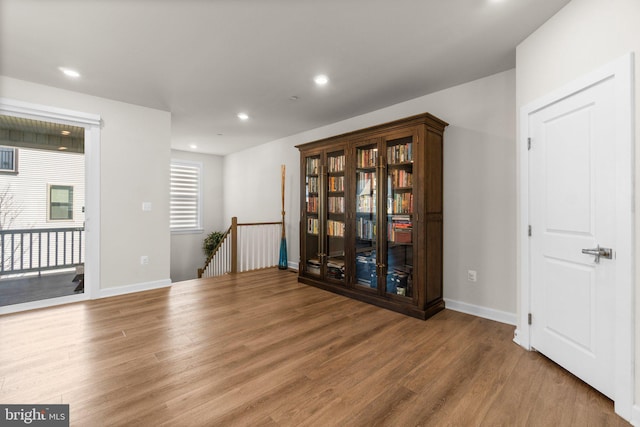 interior space with an upstairs landing, recessed lighting, baseboards, and wood finished floors