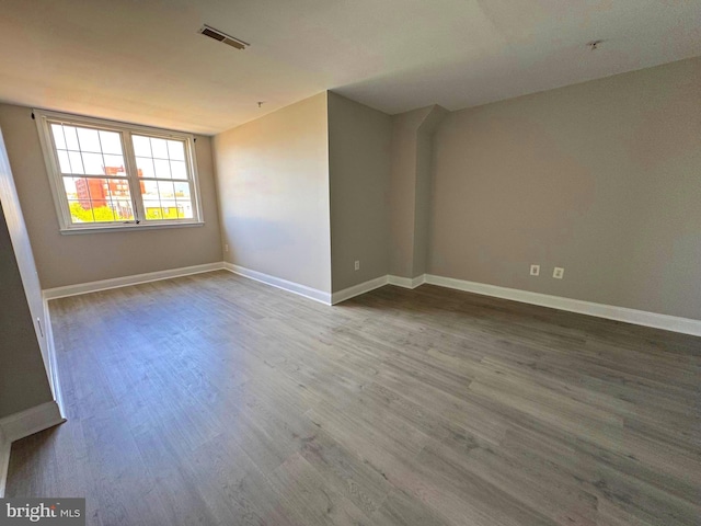 spare room featuring baseboards, wood finished floors, and visible vents