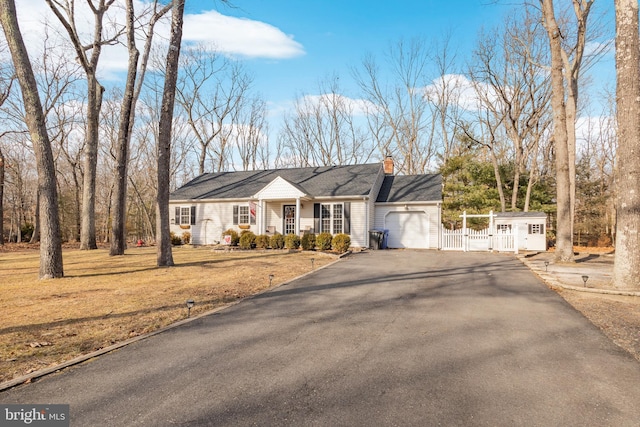 view of front of house featuring a chimney, aphalt driveway, an attached garage, a gate, and fence